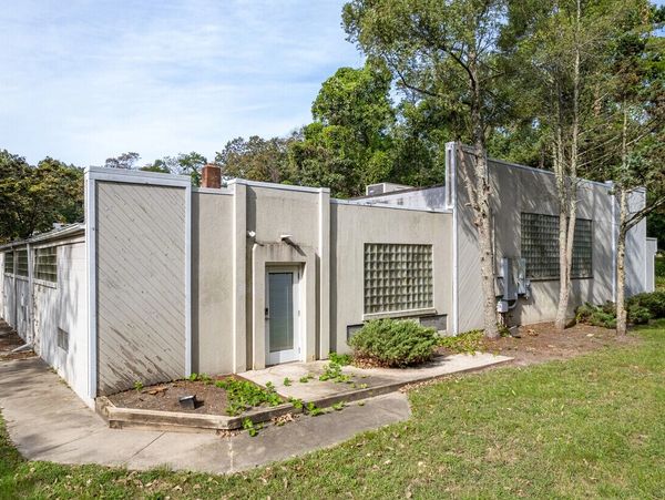 Modern single-story house with concrete walls and glass block windows.
