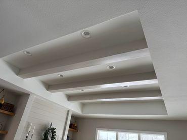 Modern ceiling design with recessed lighting and beams.