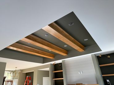 Ceiling with wooden beams and recessed lighting in a modern room.