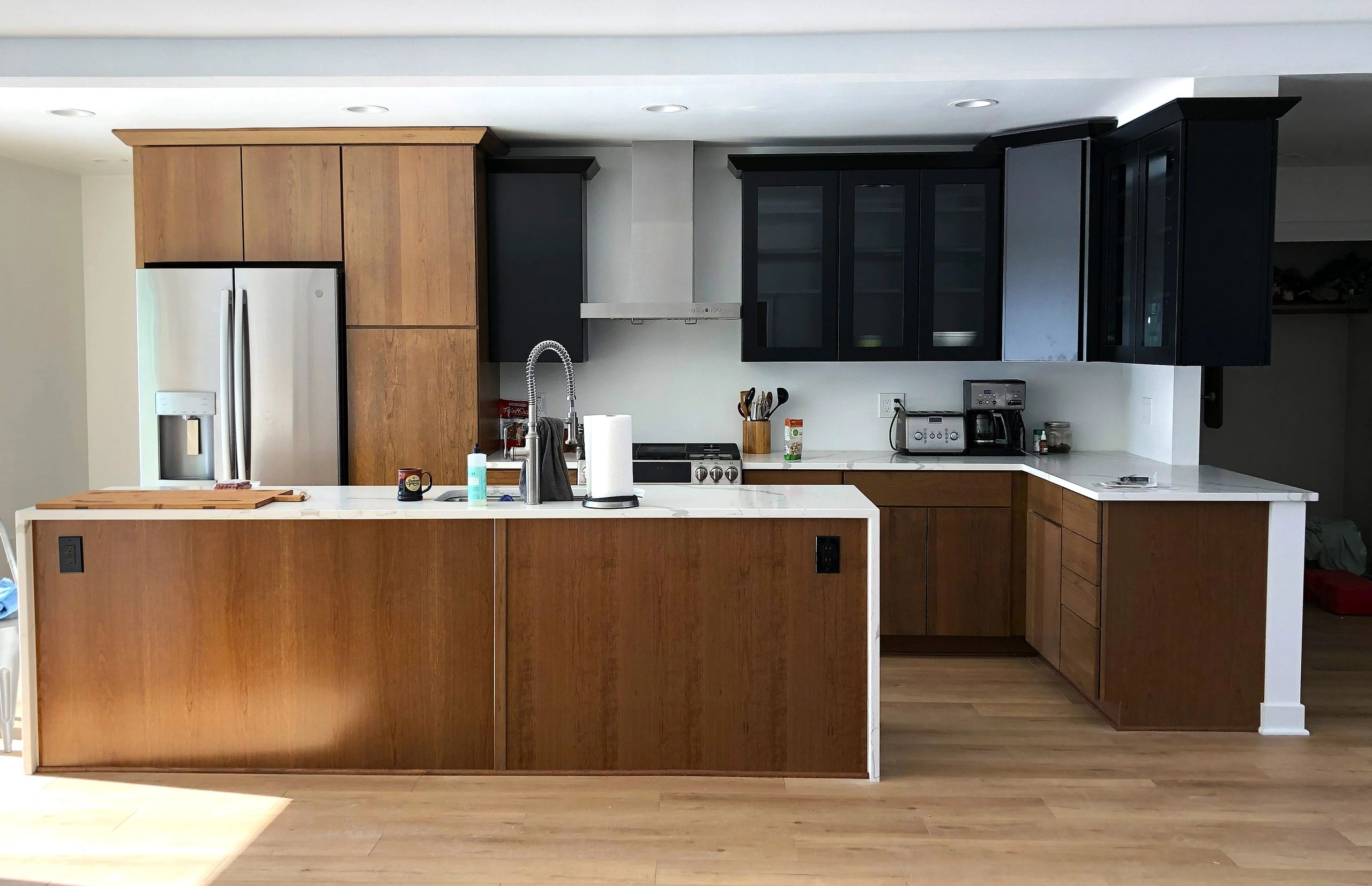 Modern kitchen with wood and black cabinets, stainless steel appliances, and a large island.