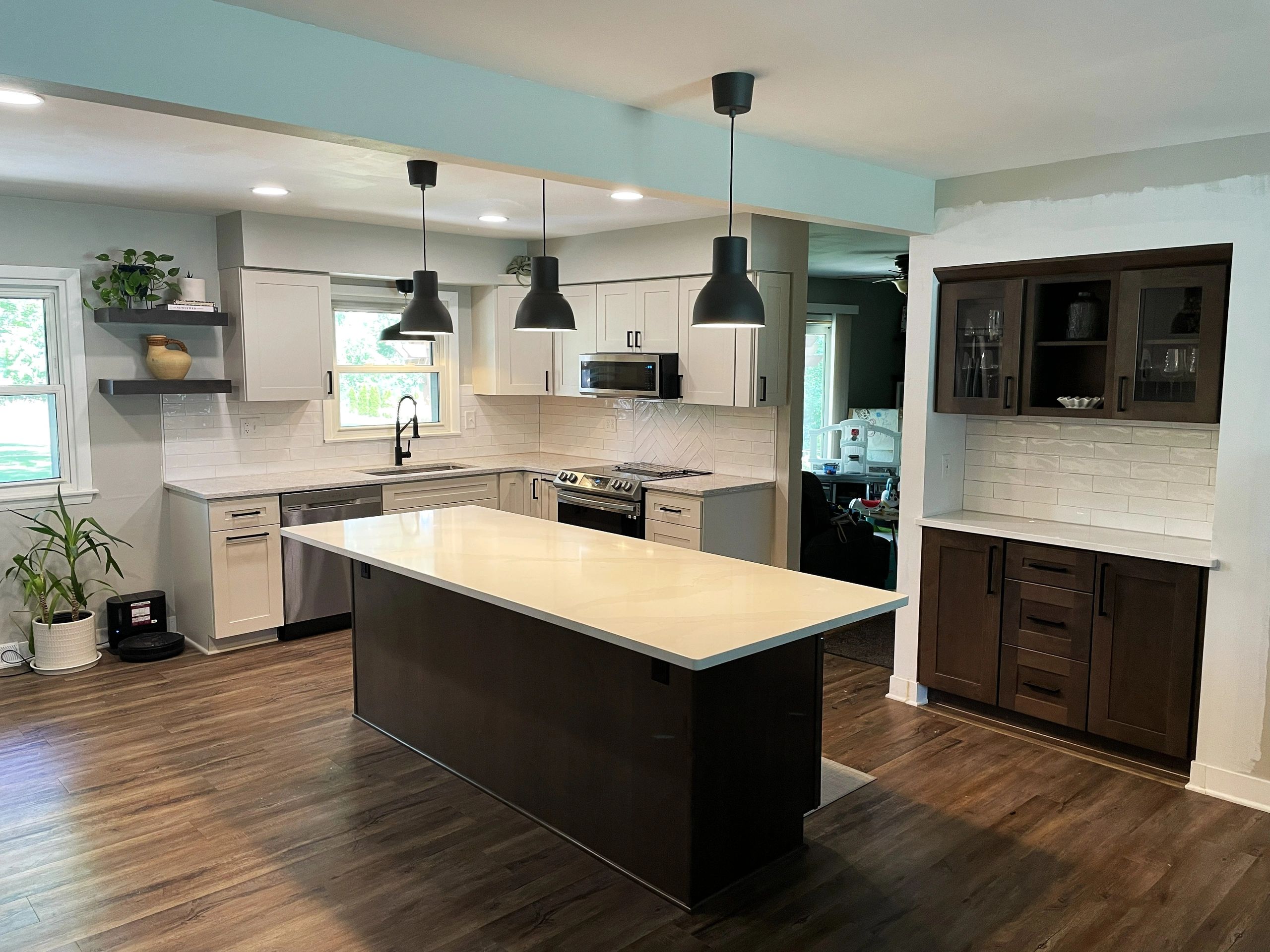Modern kitchen with island, pendant lights, and wood flooring.