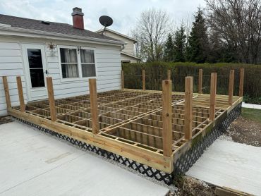 Wooden frame structure for a deck being built beside a house.