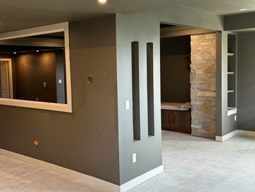 Interior of a modern basement under construction with gray walls and recessed lighting.