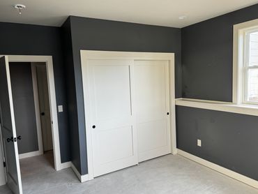 Empty room with dark gray walls and white sliding closet doors.