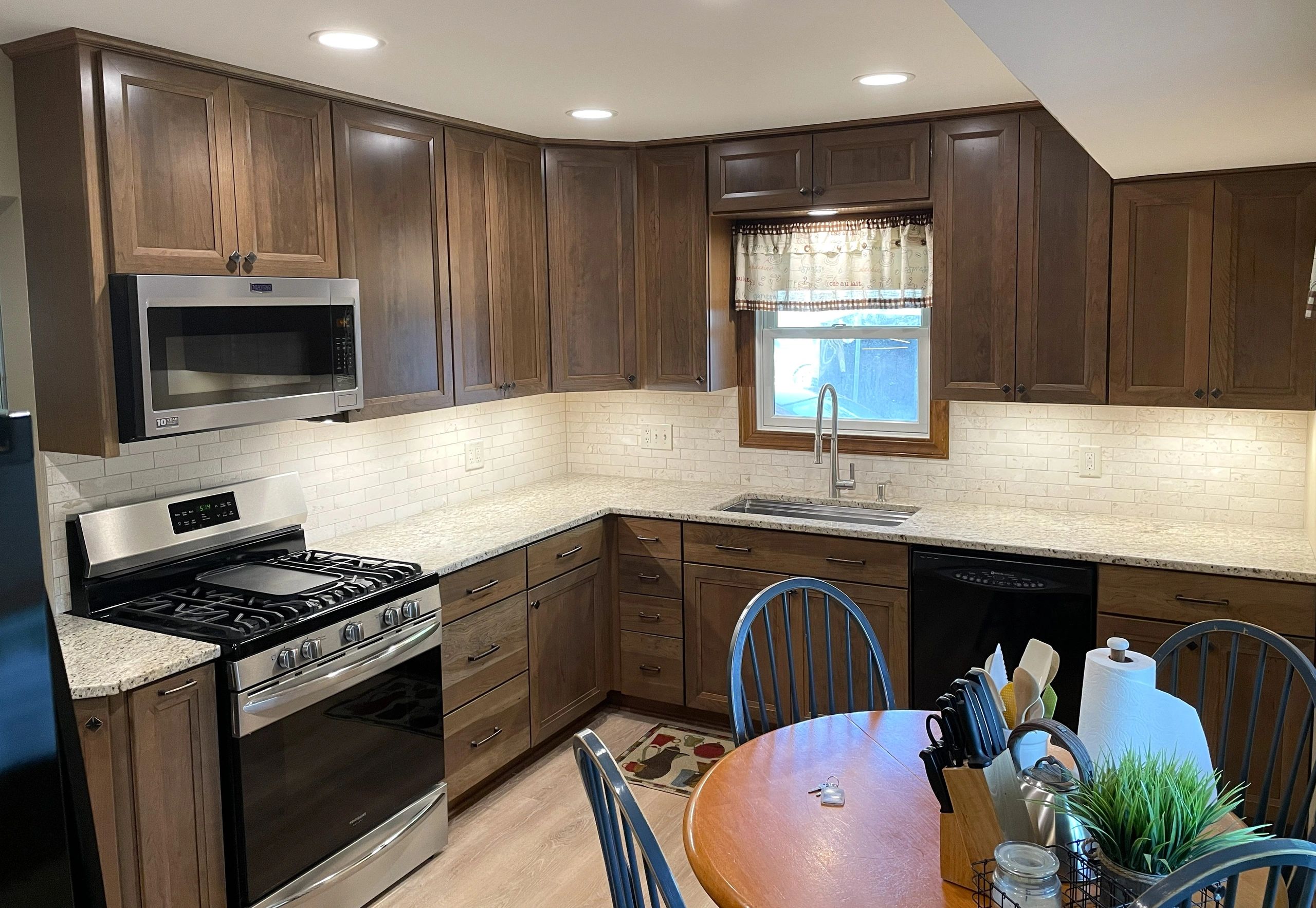 Modern kitchen with wooden cabinets, stone countertops, tile backsplash,  and SS appliances
