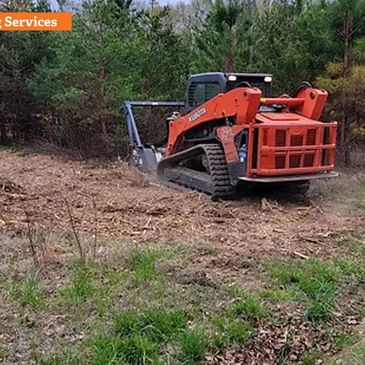 Orange forestry mulching machine clearing land in a wooded area.