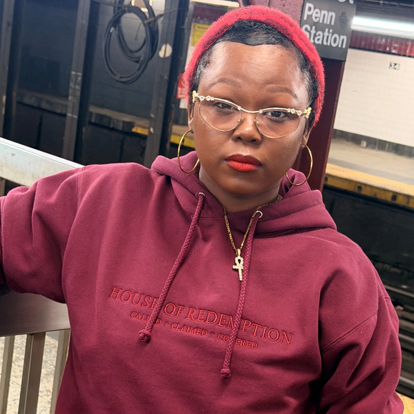 Person in a maroon hoodie and red beanie at Penn Station.