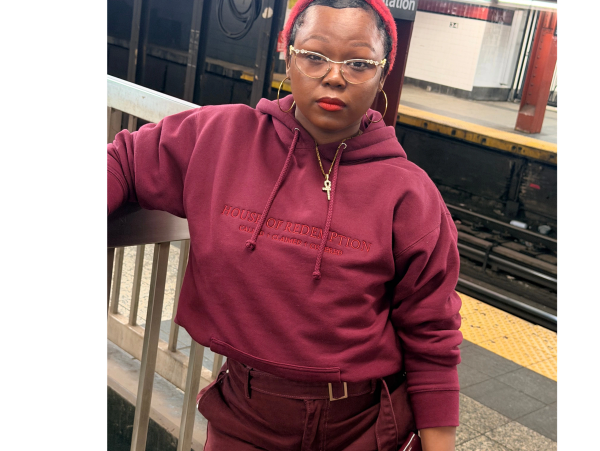 Person in a maroon hoodie and red beanie at Penn Station.