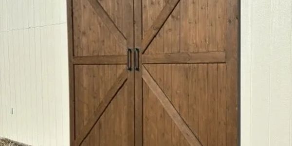 Rustic wooden barn doors on a white exterior wall.