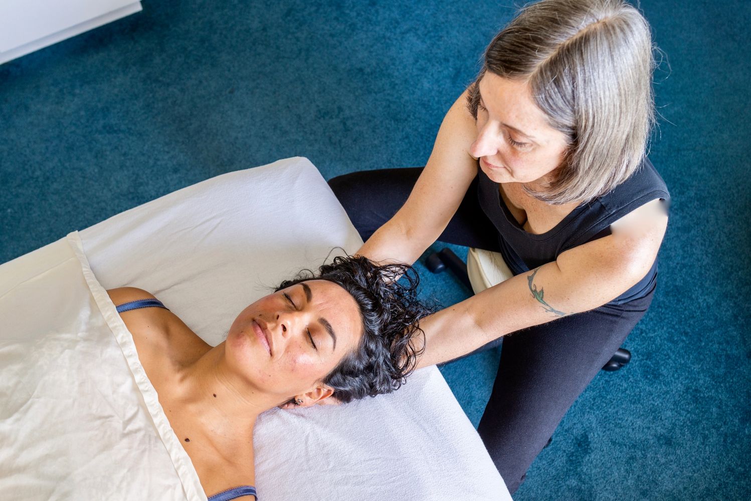 Client with peaceful expression on massage table receiving hands on Rolfing SI neck work. 