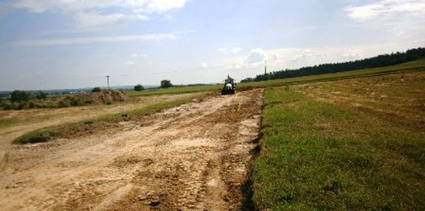 A tractor working on a dirt road in a rural field.