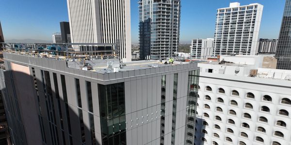 Workers on a rooftop in a city with tall buildings around.