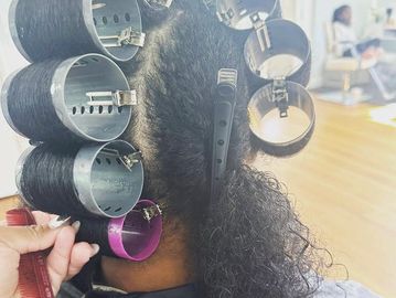 Hair rollers set in curly hair with a clip.