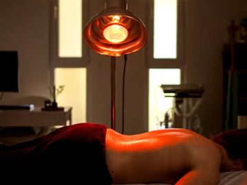 Person receiving heat therapy on back under a heat lamp.