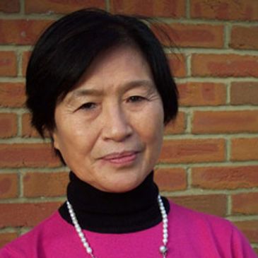 Portrait of a woman wearing a pink top and pearl necklace.