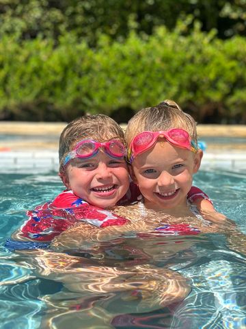 Two swimmers preschool age smiling in the water. Private swim instructor private swimming lessons