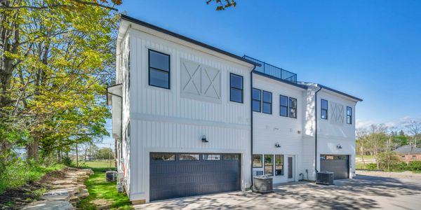 Modern white two-story townhouses with garage doors under a clear blue sky.