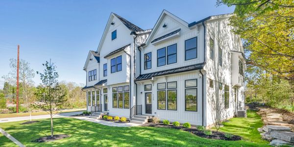 Modern white townhouse with large windows and landscaped lawn under clear blue sky.