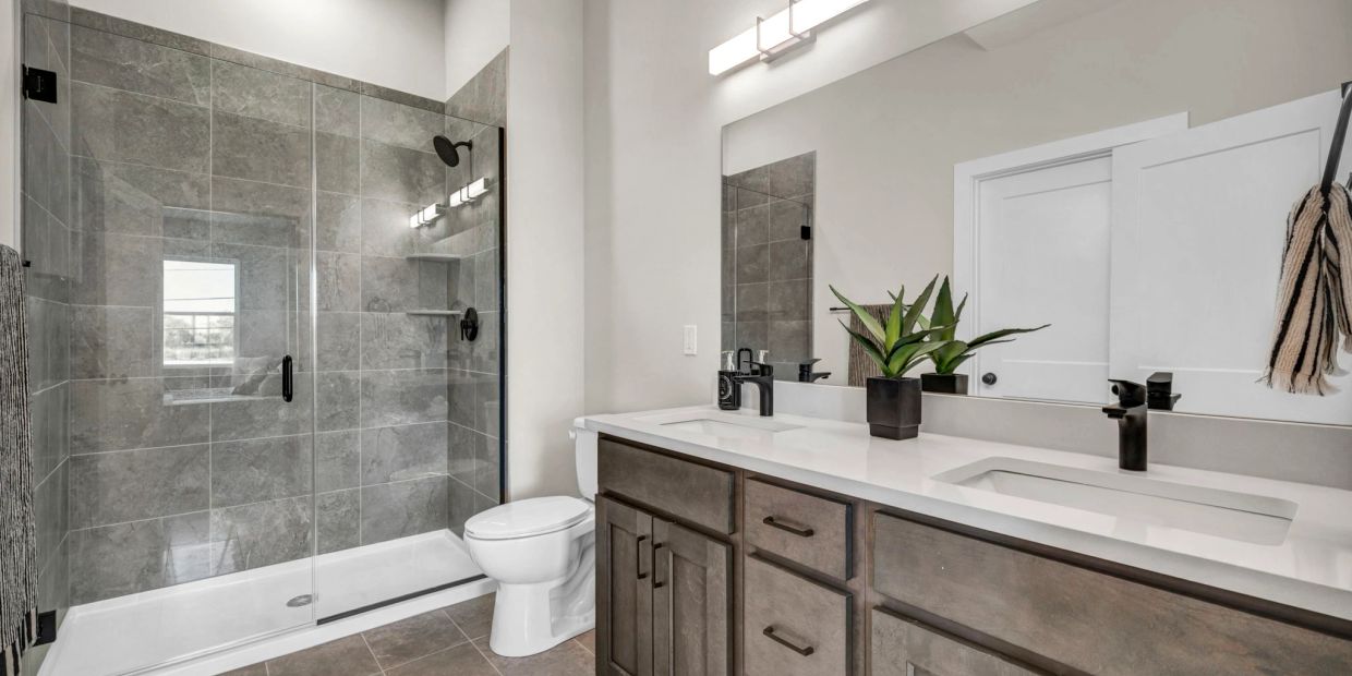 Modern bathroom with glass shower and double sink vanity.