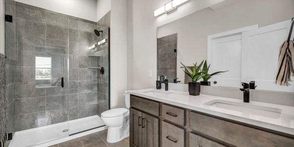 Modern bathroom with glass shower and wooden vanity.
