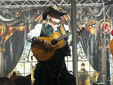 Musician in elaborate costume playing guitar on stage.