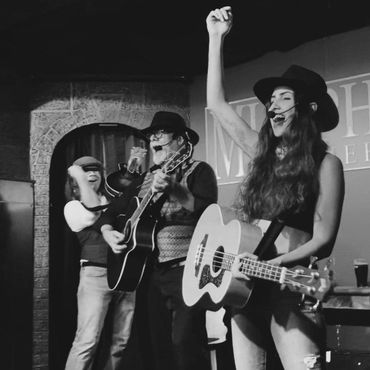 Three musicians joyfully performing on stage, playing guitars and singing.