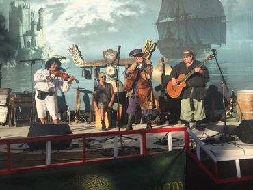 Musicians in pirate-themed costumes perform on stage with a ship backdrop.