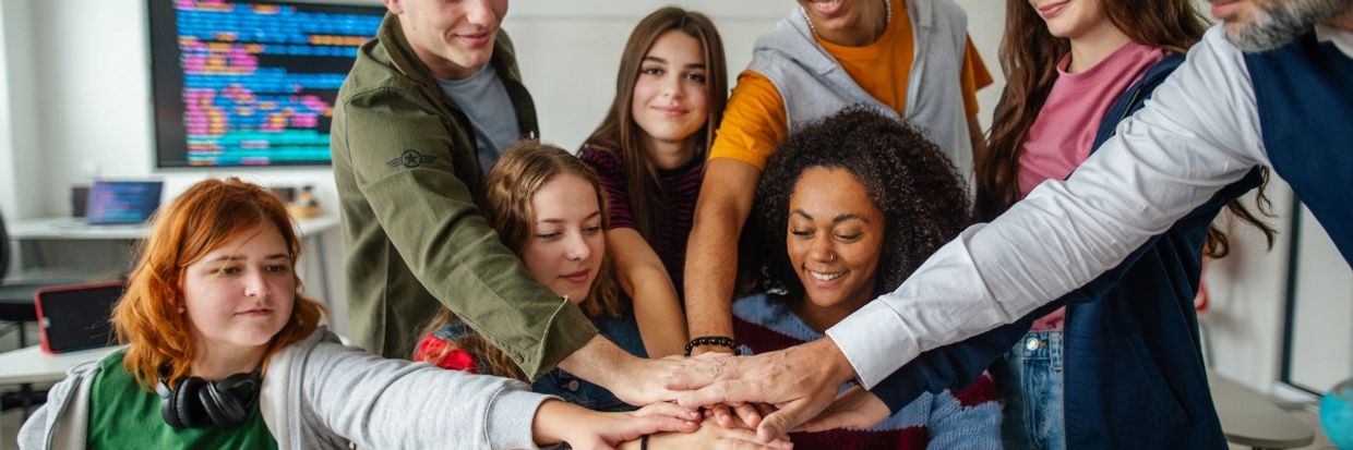 A diverse group of people joining hands in a show of teamwork and unity.