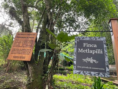 Entrance signs to Finca Metlapilli conservation area in a forested setting.