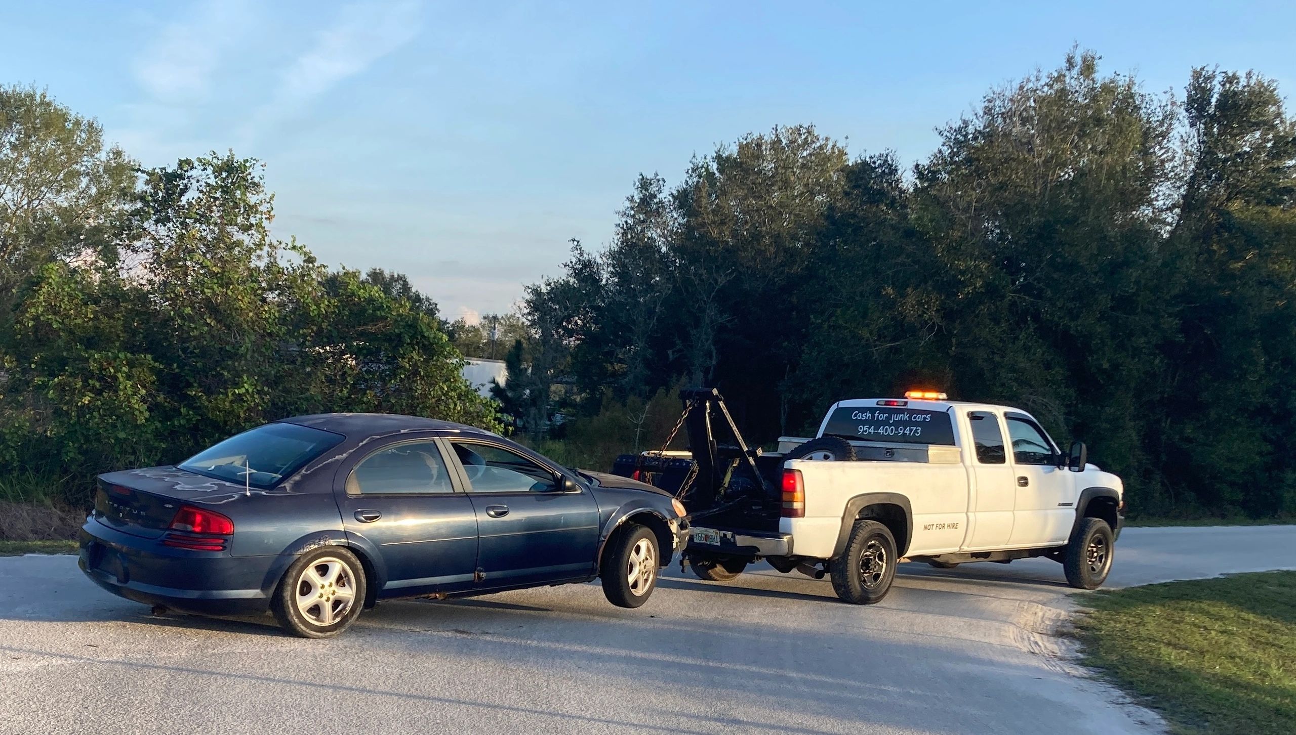 A Dodge Stratus hooked up and heading to the junkyard 