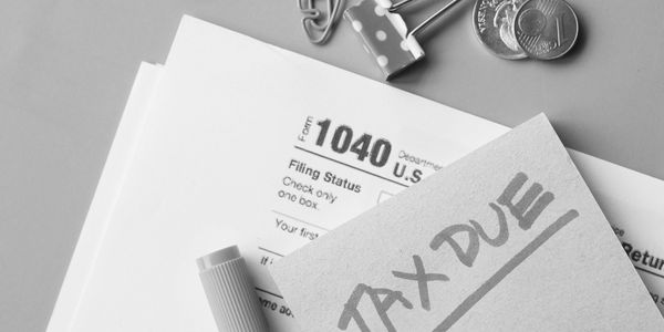 A Form 1040, a note labeled ‘Tax Due,’ and a penny on a table
