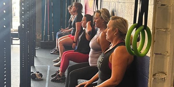 Group of women doing wall sits in a gym workout session.