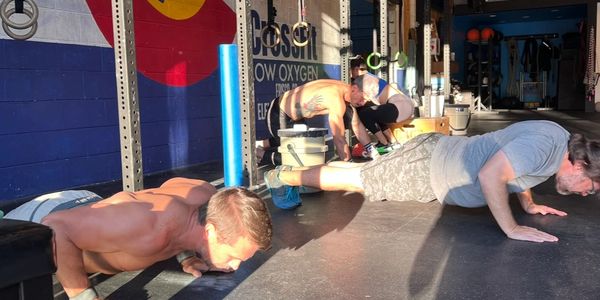 People doing push-ups in a gym with sunlight streaming in.
