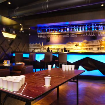 Indoor bar with a beer pong table set up for a game.