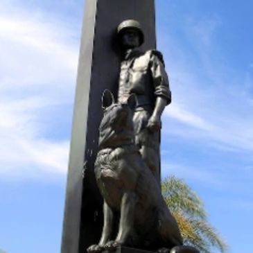 Statue of a soldier and a dog against a blue sky.