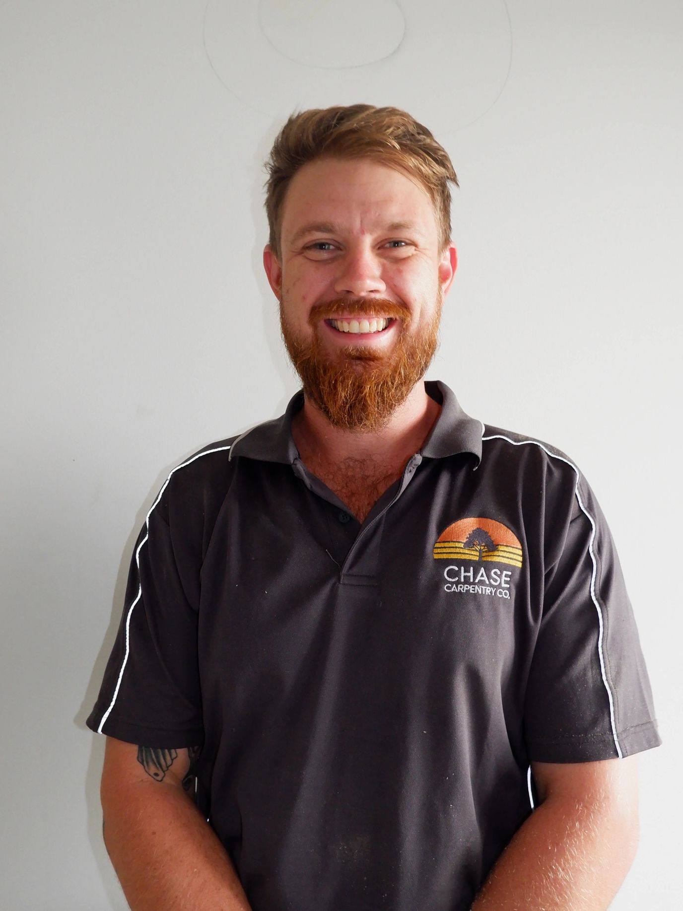 Smiling man wearing a black Chase Carpentry Co. shirt.