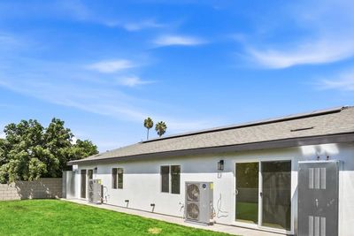 White home with sliding doors and a lawn in the backyard