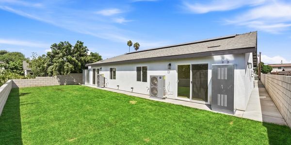 White home with sliding doors and a lawn in the backyard