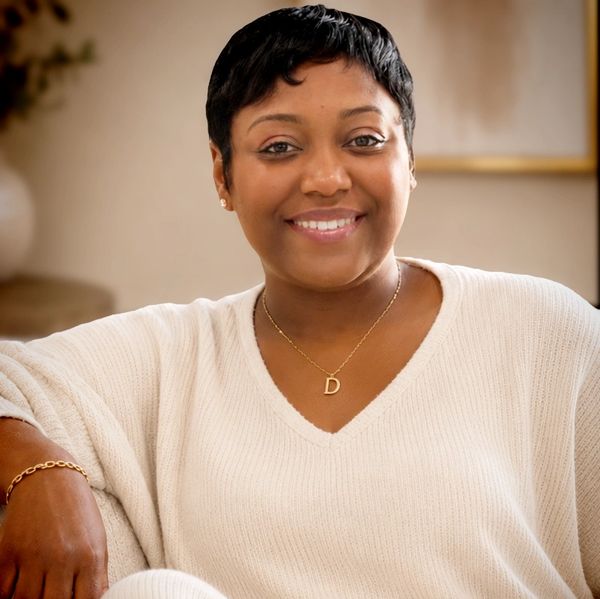 Smiling woman in a white sweater with a gold necklace.