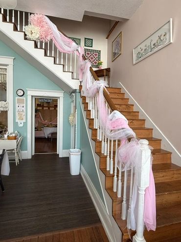 Staircase decorated with pink and white tulle and flowers for a celebration.
