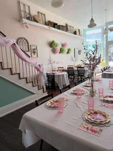 Elegant dining setup with floral decorations and pink accents in a bright room.