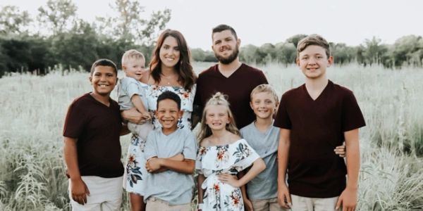 Smiling family of eight in a field.