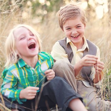 Two kids laughing joyfully outdoors.
