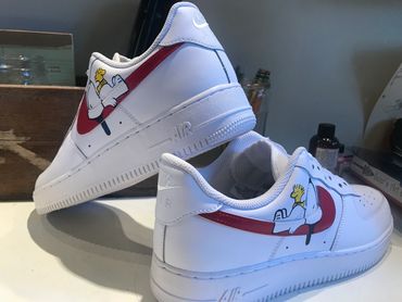 White sneakers with cartoon character and red swoosh design.