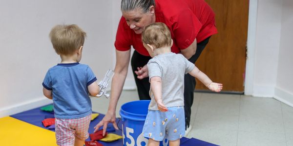 An educator leans over for hands-on learning with small children and a learning game. 