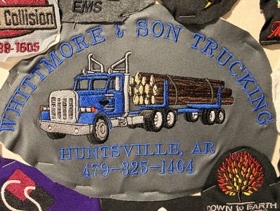 Embroidered logo of Whitmore &amp; Son Trucking with a blue logging truck and contact info.
