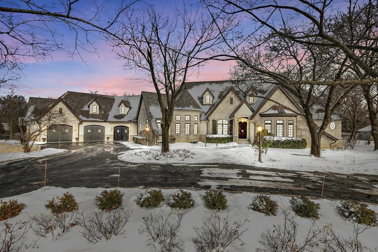 Large house with snow and bare trees at dusk.