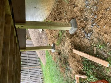  New pressure-treated deck support posts set in concrete to replace deteriorated structural supports