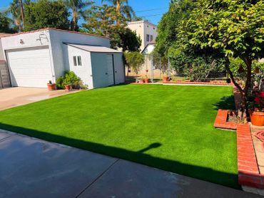 A well-maintained lawn with a white garage and surrounding greenery.