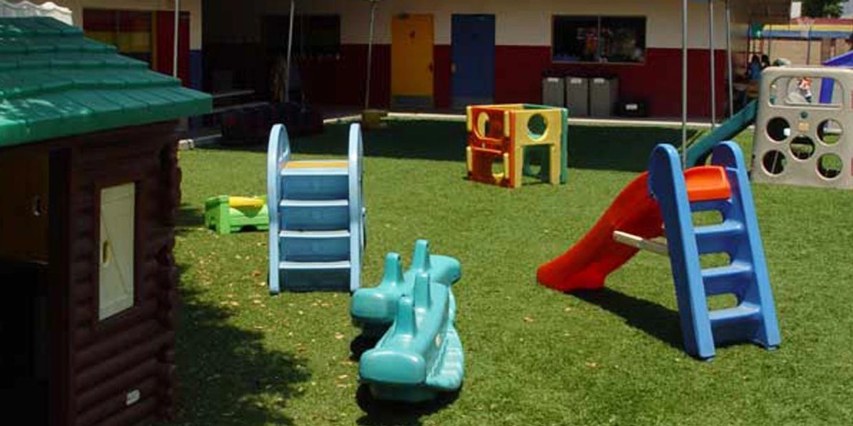 Outdoor playground with colorful slides and play structures on artificial grass.